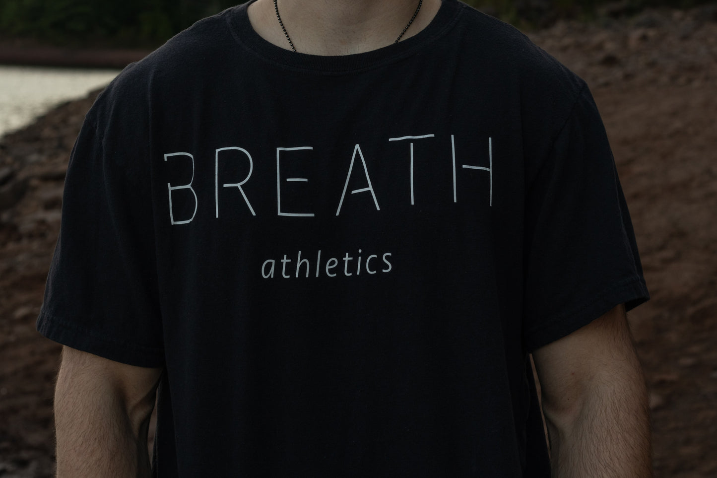 A person showcasing the chest of their Breath black t-shirt, featuring the brand name prominently displayed across the front.