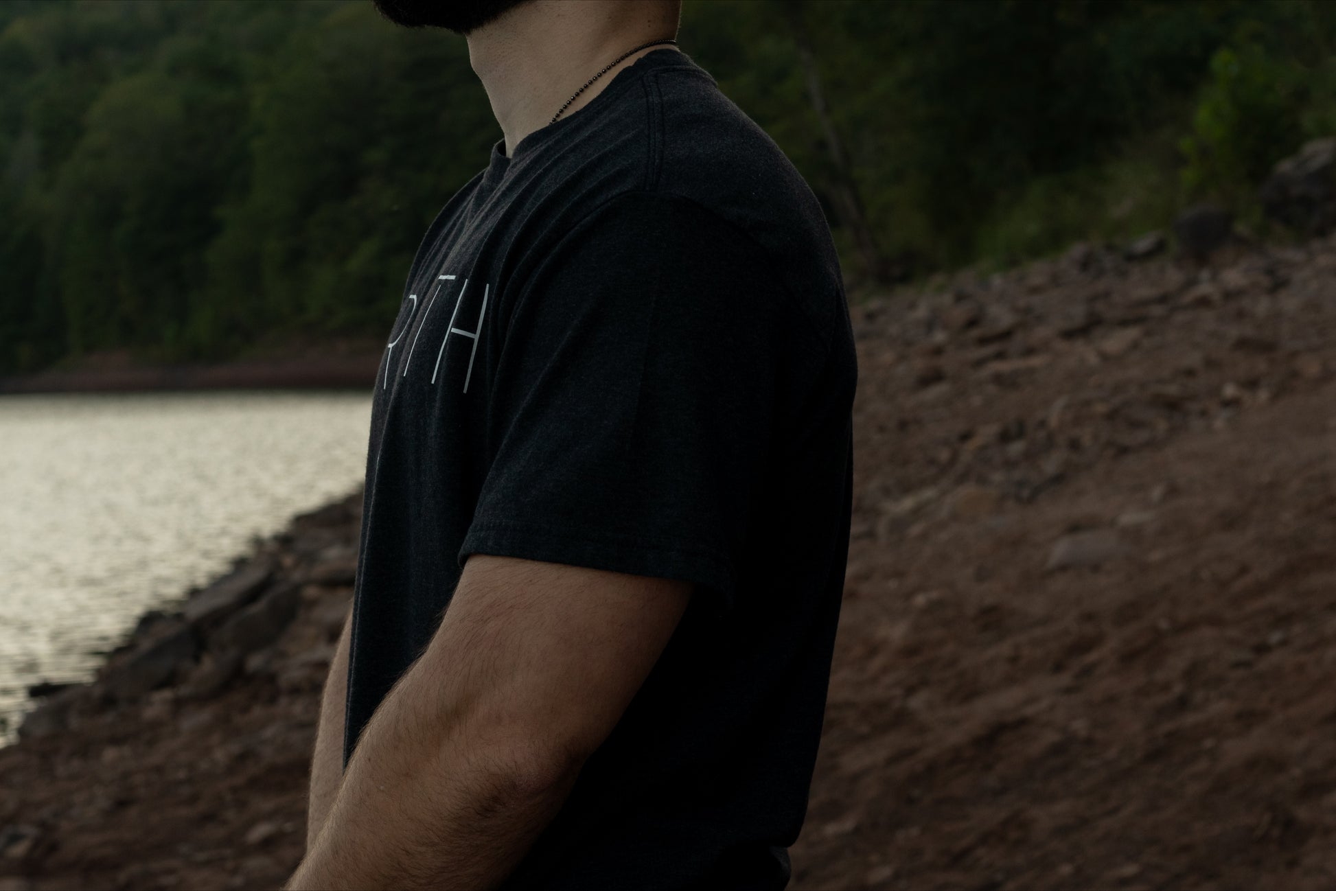 Side View of the Breath Balance 50/50 Up-cycled Cotton Recycled Polyester.  Short Sleeve Black T Shirt With the World Breath Across the chest and the Breath Emblem Between the Shoulder Blades. 